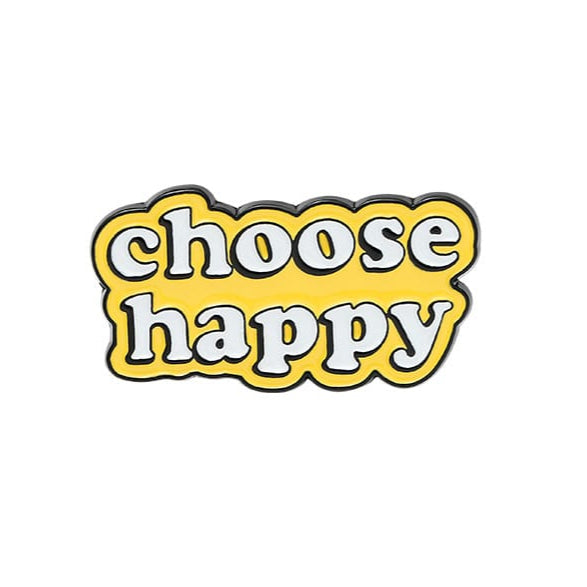 An enamel pin with the text 'choose happy' in a yellow font on a white background.