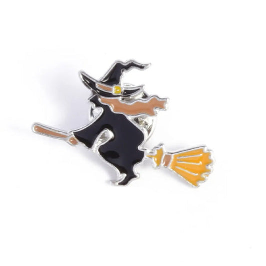 An enamel pin depicting a witch riding a broomstick, primarily in black and orange colors.